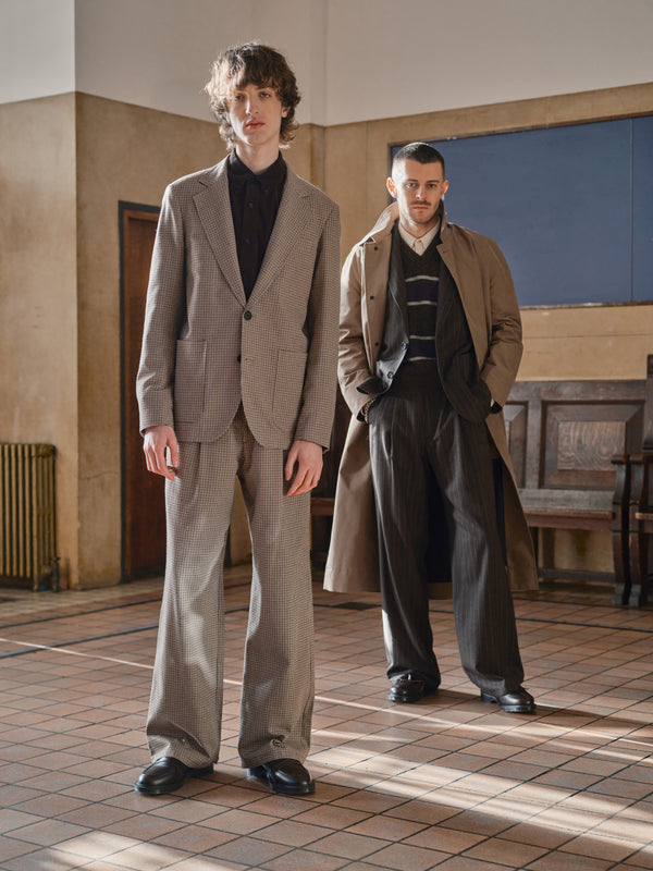 Two men in a panelled hall wearing an Oliver Spencer beige corduroy suit and a long wool overcoat