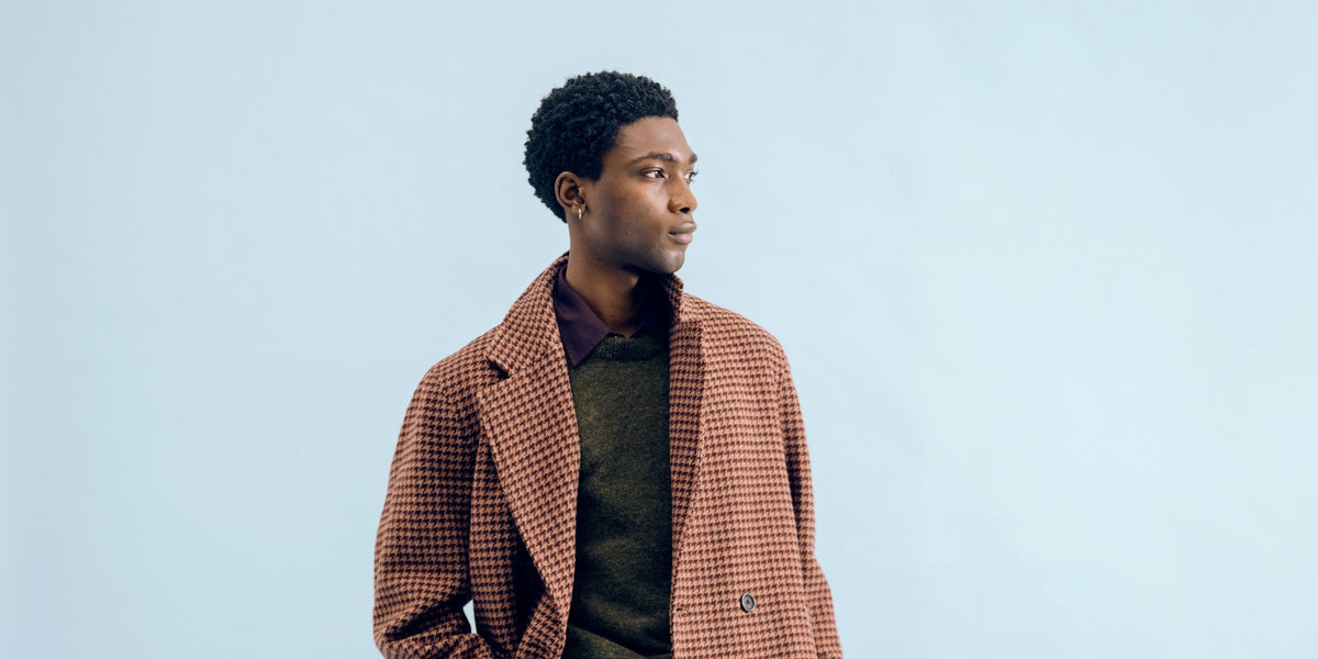 A burgundy and pink houndstooth Tamworth double breasted overcoat against a pale blue backdrop