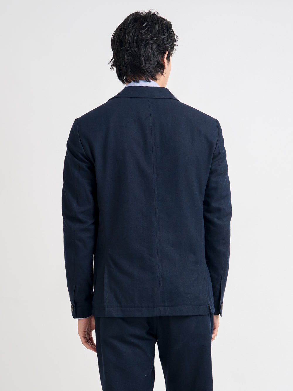 Closer up back shot of model wearing Oliver Spencer Men's Unstructured Peak Lapel Navy Cotton Jacket