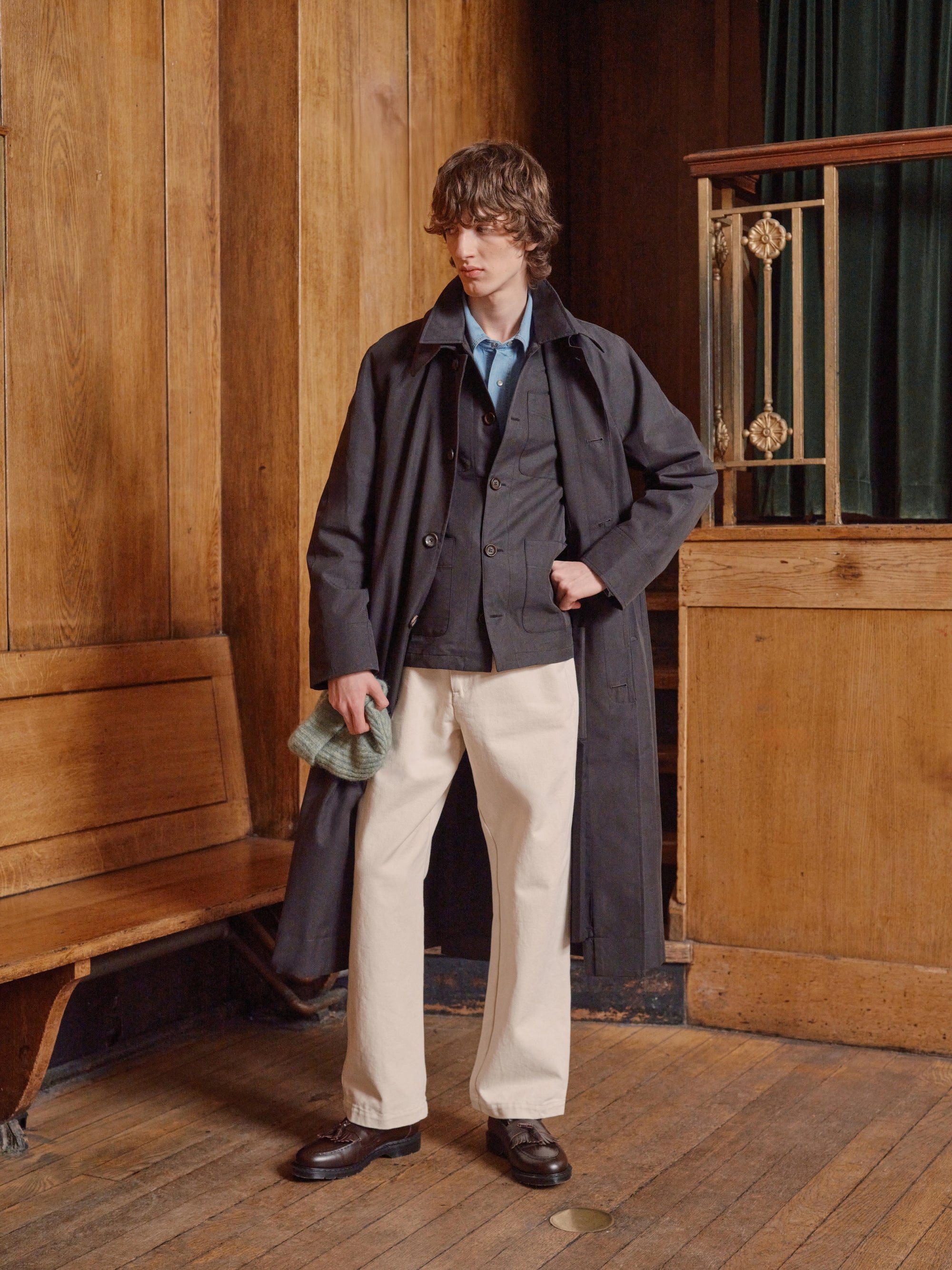Model in a grey coat, pale blue shirt and ecru trousers