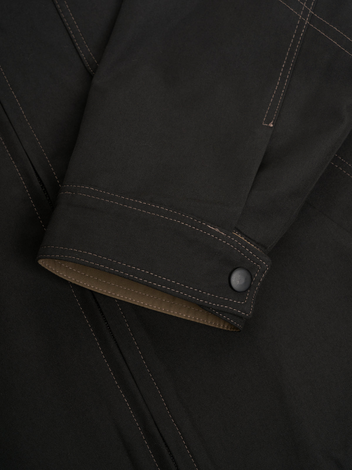 Cuff. A press stud on a stitched cuff band.