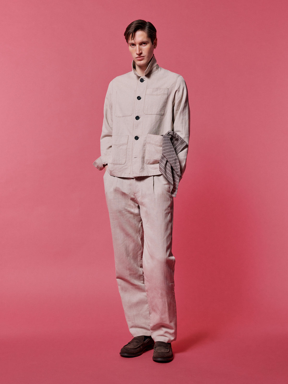 Sand jacket and matching trousers with a neckerchief, against a pink backdrop.