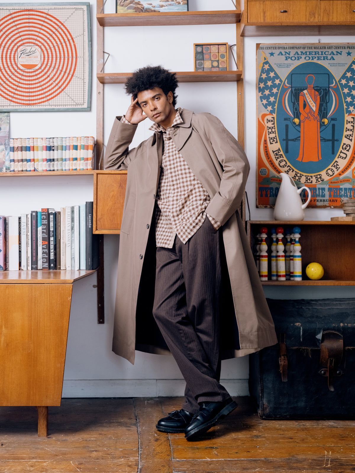 Khaki Lothian coat over a brown check shirt with brown pleated trousers.