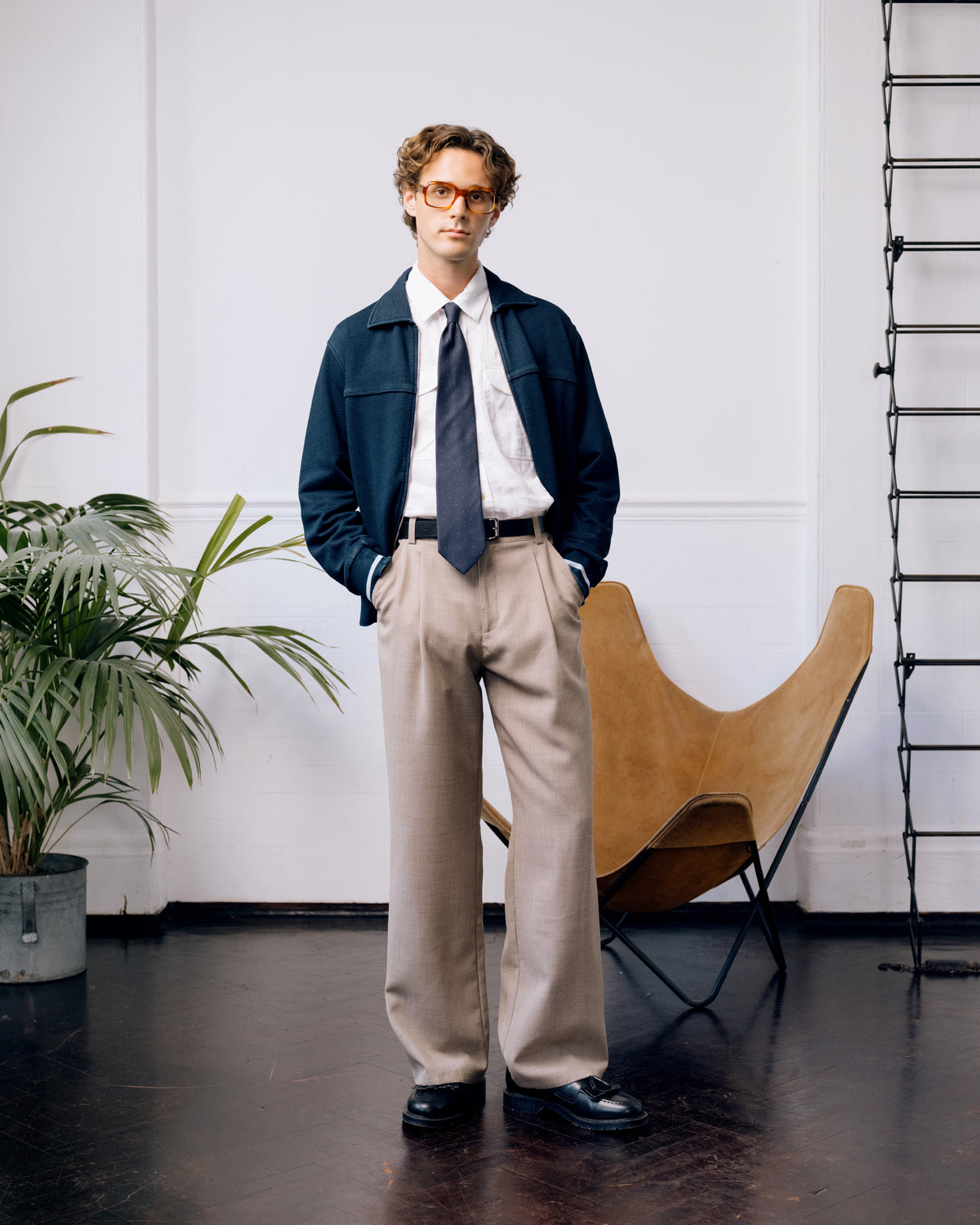 Indigo Harrison jersey jacket over a white short sleeve shirt and tie, with beige Orsman trousers and black tassel loafers.