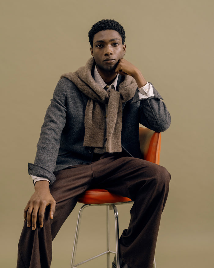 A charcoal Solms jacket with a mushroom Soane scarf over the shoulders, seated
