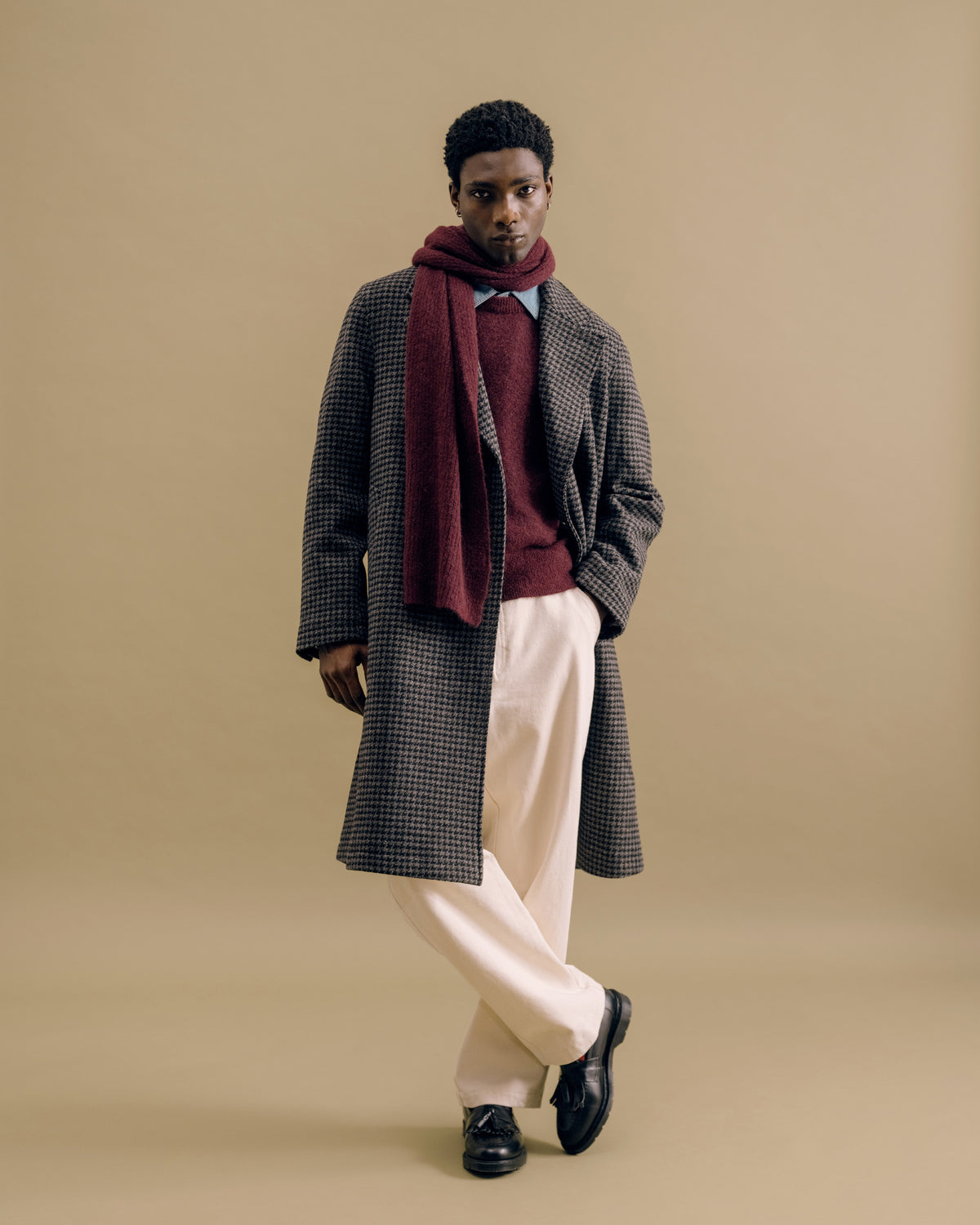 A charcoal houndstooth overcoat with a burgundy Soane scarf, burgundy Blenheim crew neck and cream trousers