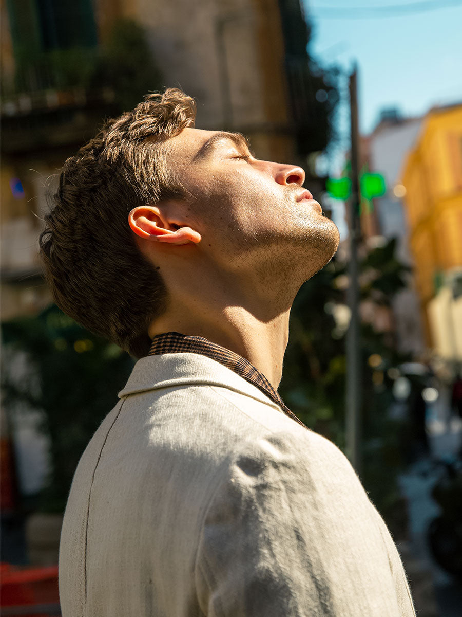 Oliver Spencer Summer 22 in Naples, look 7. Cream linen shirt, head tilted back in low sun.