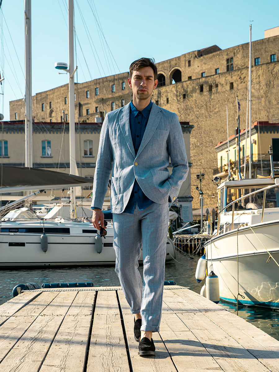 Oliver Spencer Summer 22 in Naples, look 15. Pale blue suit, walking the marina past moored yachts.