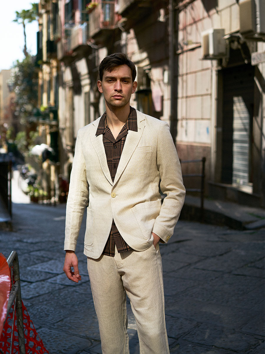 Oliver Spencer Summer 22 in Naples, look 23. Ivory suit on a narrow Naples street.